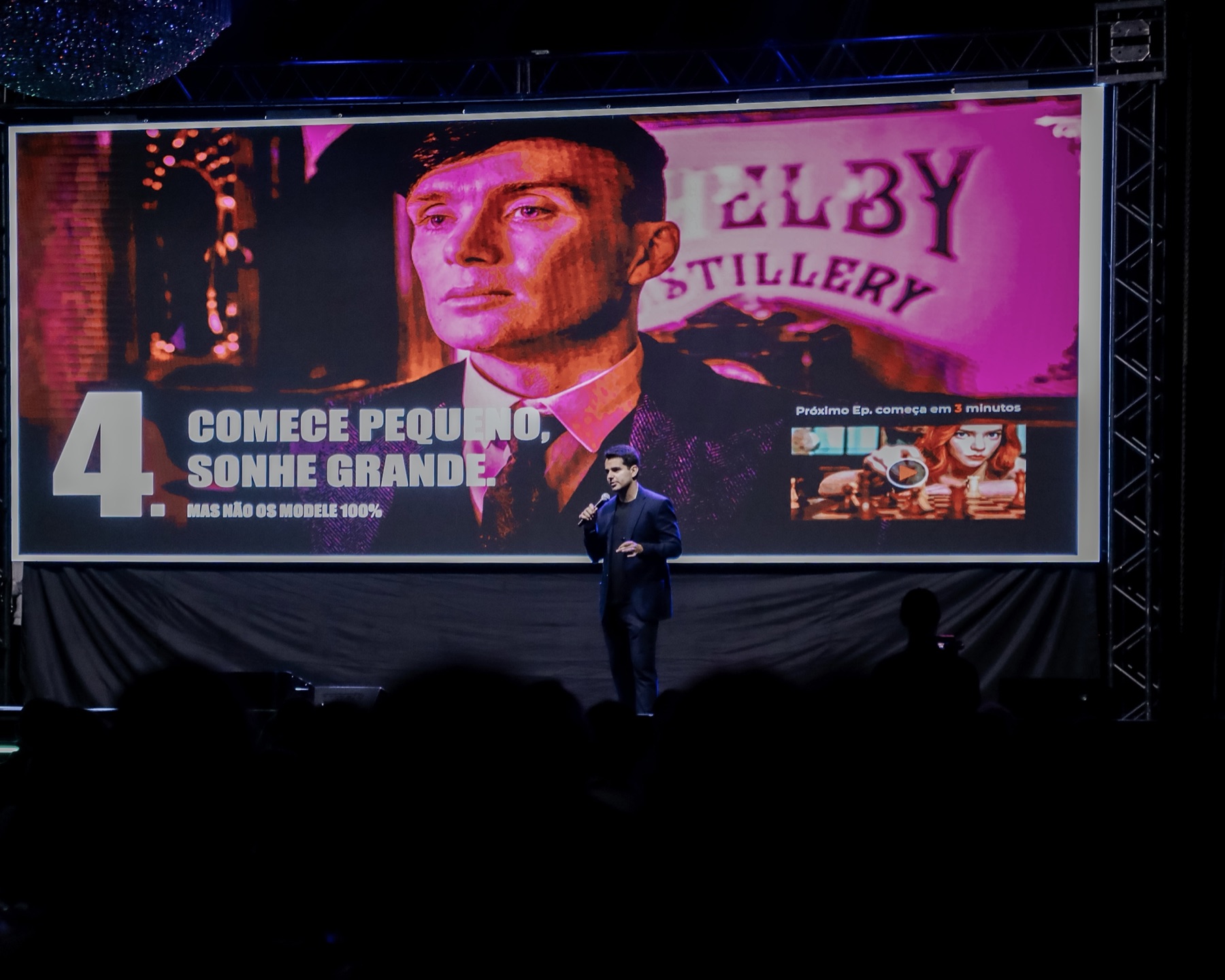 Leonardo Capel palestrando em um palco, diante de um telão